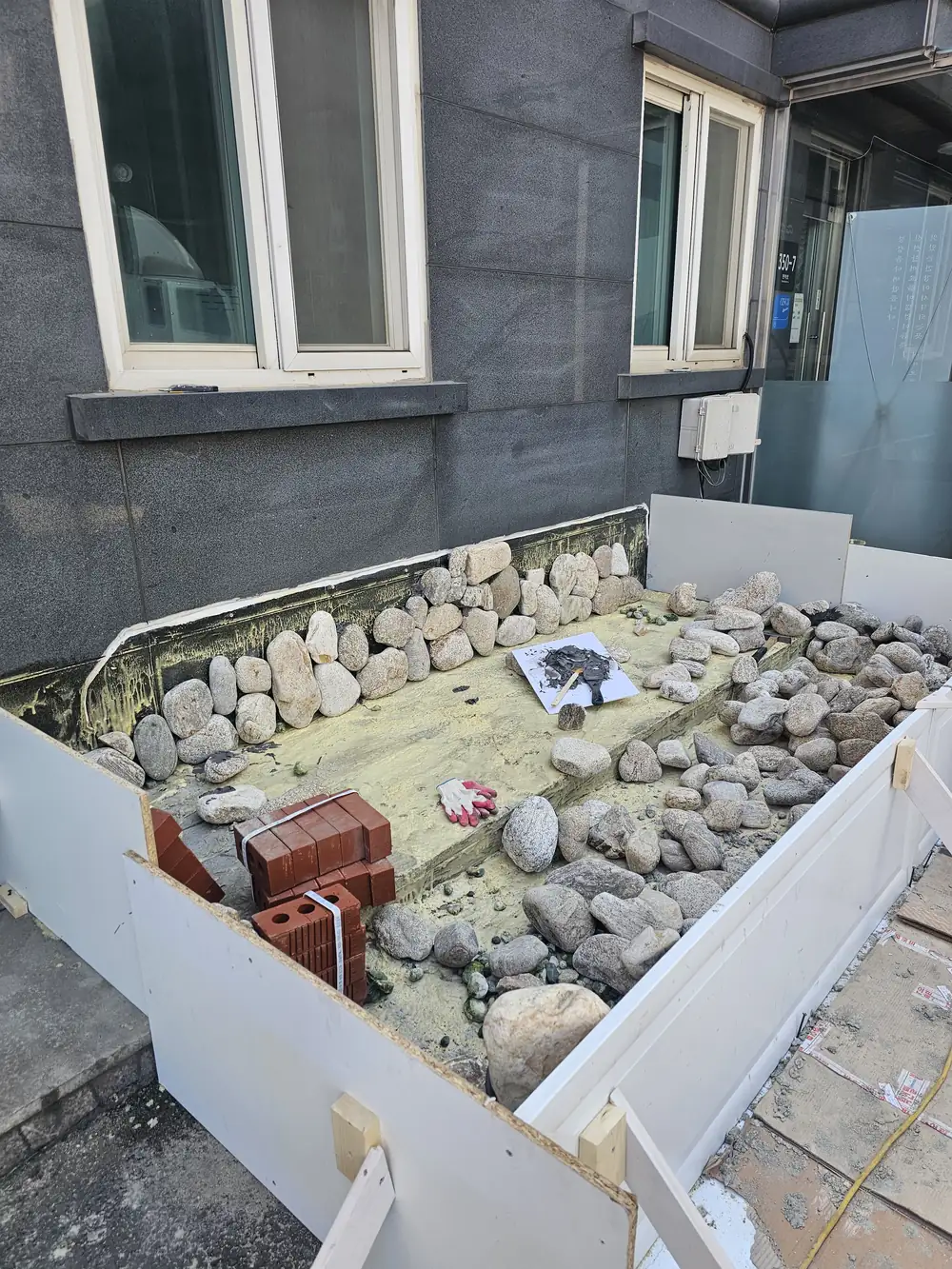 인공연못 재시공 진행 중 합판 거푸집 안에 자연석을 배치한 모습